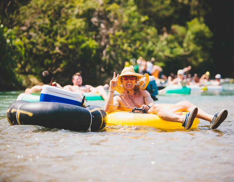 Guy giving a peace sign with his fingers on the river