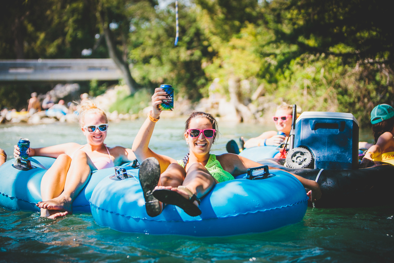 Three girls on the river cheersing with cooler